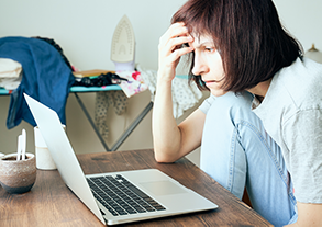 Image of woman feeling very stressed while looking at her laptop computer screen. Nailcarehq.com